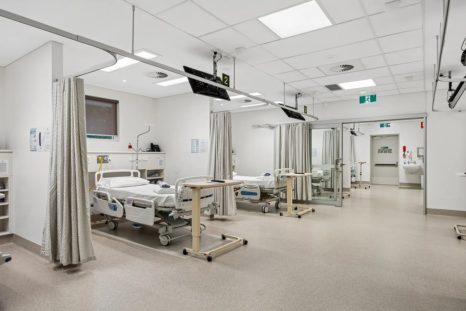 A hospital ward with beds separated by curtains